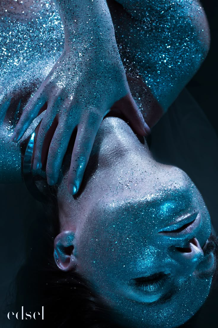 a woman covered in blue glitter laying down