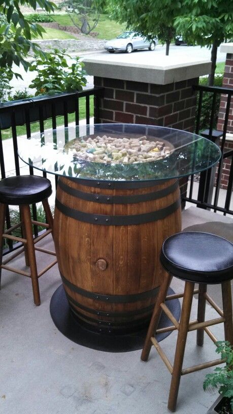 a wooden barrel sitting on top of a patio next to two stools and a table