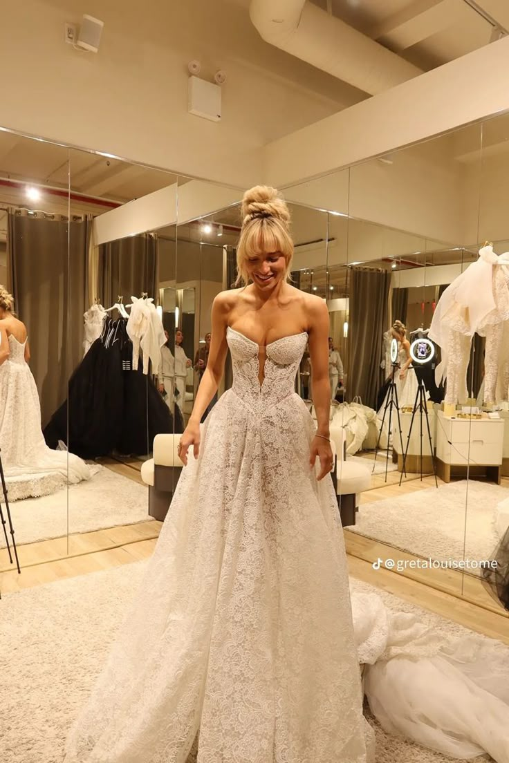 a woman standing in front of a mirror wearing a wedding dress