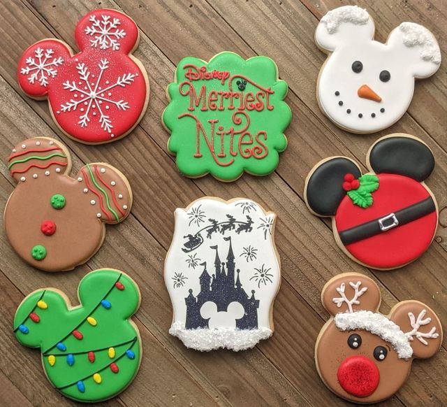 some decorated cookies are sitting on a wooden table with snowman, santa clause, and mickey mouse