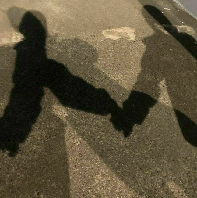 the shadow of two people holding hands in front of a skateboarder's reflection