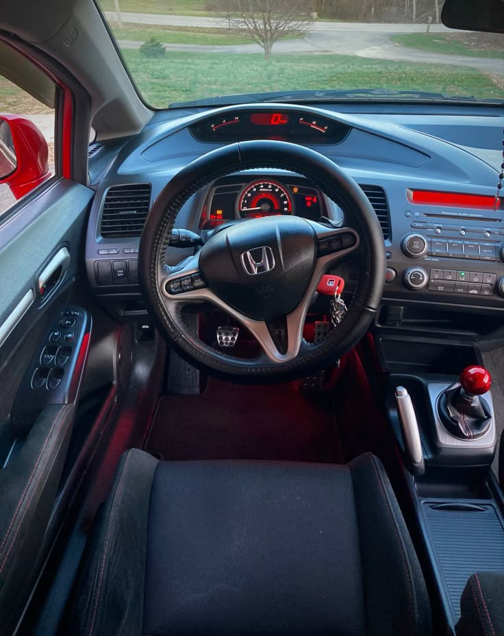 the interior of a car with red and black dash lights, steering wheel controls, dashboard