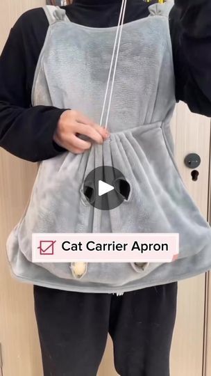 the cat carrier apron is being held by someone