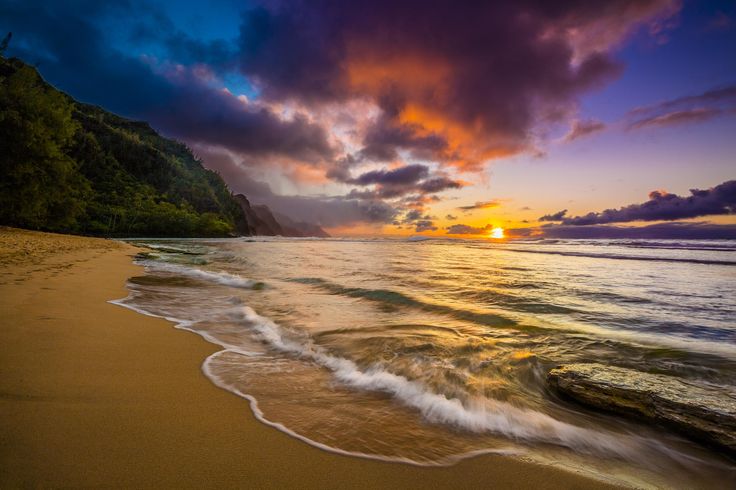 the sun is setting over the ocean with waves crashing on the beach and trees in the background