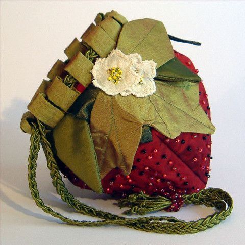 a handbag made out of fabric with flowers and leaves on the front, sitting on a white surface