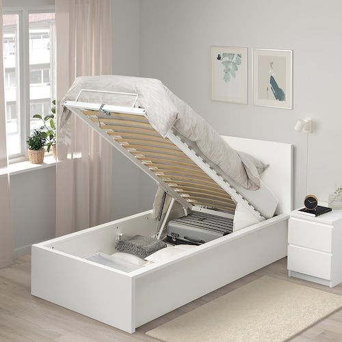 a white bed frame with a pull out mattress and storage compartment underneath it in a bedroom