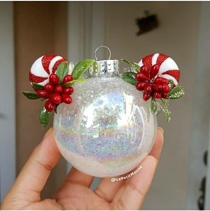 a hand holding a christmas ornament with candy canes and bows on it