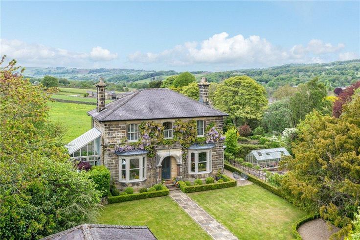 an aerial view of a house in the middle of a lush green field with trees and bushes