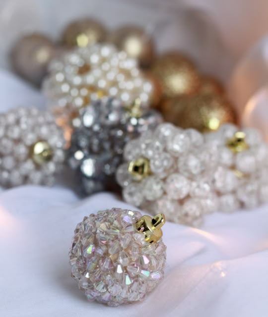 a bunch of beads that are sitting on a white cloth with gold and silver balls