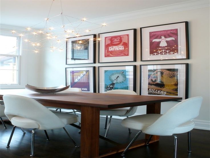 a dining room table with chairs and pictures on the wall