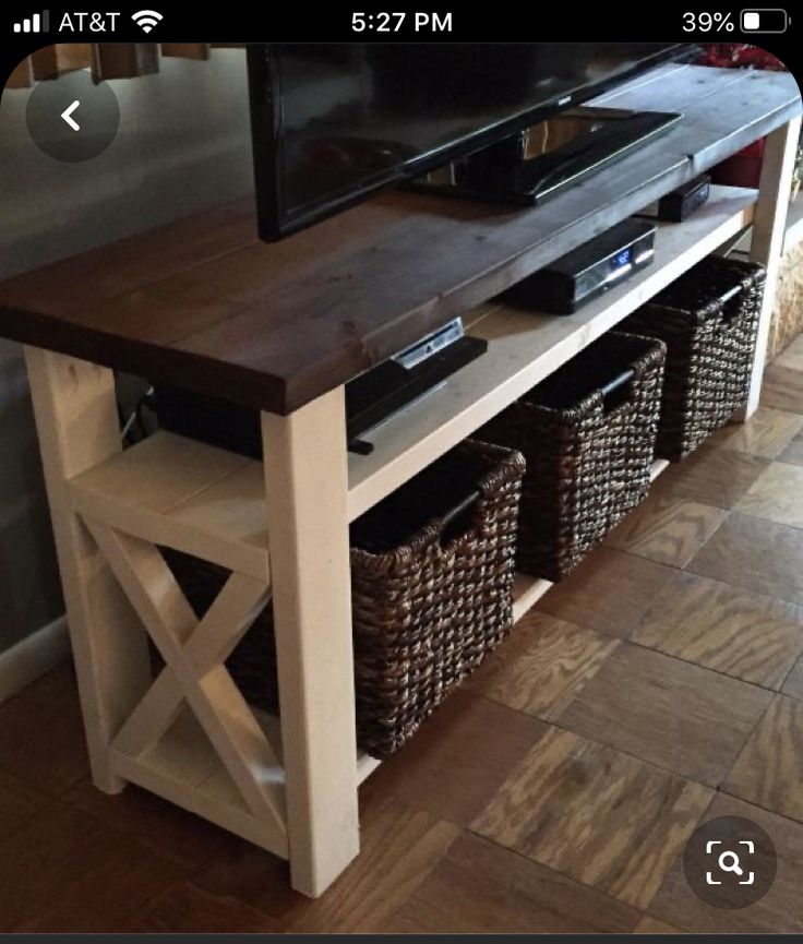 a flat screen tv sitting on top of a wooden table next to baskets filled with items