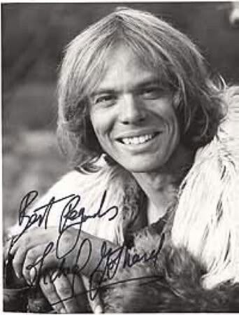 an autographed photograph of a smiling man with long hair and fur on his shoulders