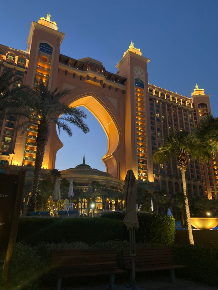 the hotel is lit up at night with palm trees