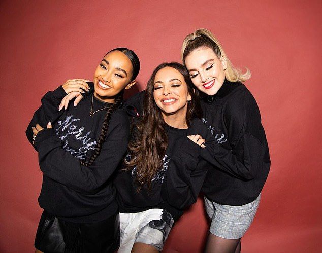 three women in black sweatshirts are posing for a photo with their arms around each other