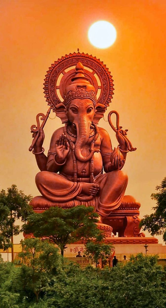 an elephant statue is shown with the sun in the background and trees around it's base