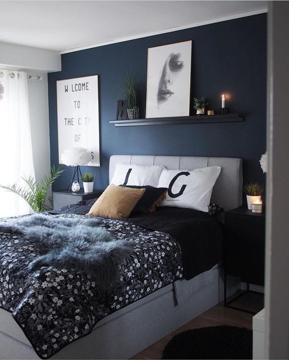 a bedroom with dark blue walls and white bedding, black comforter and pillows