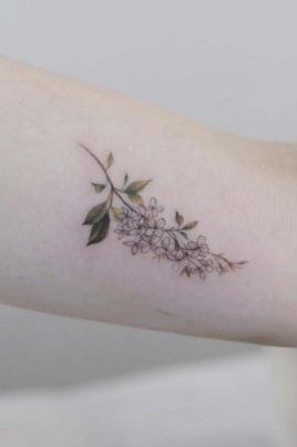 a woman's arm with flowers and leaves on the left side of her arm