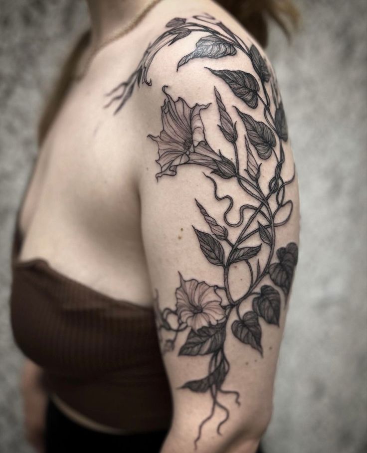 a woman's shoulder with flowers and leaves on it