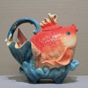 a fish shaped teapot sitting on top of a table