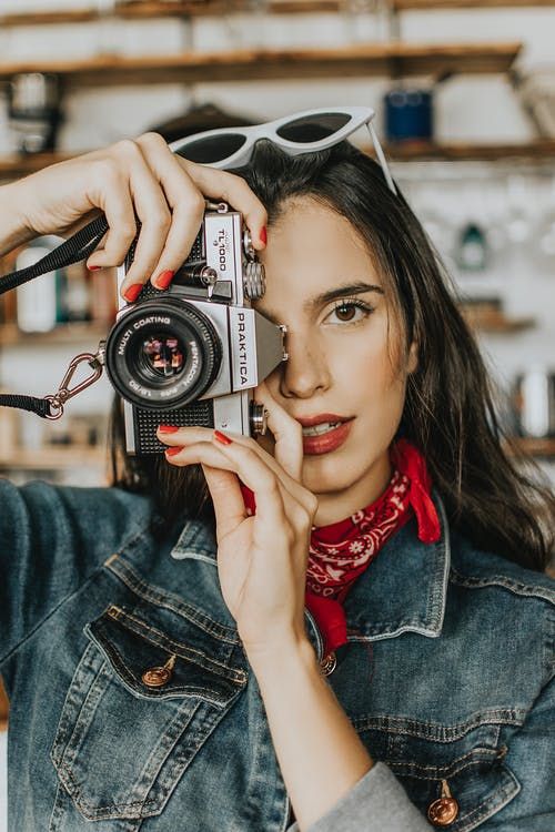 a woman holding an old camera up to her face