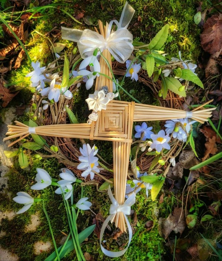 a cross made out of wicker and flowers on the ground with grass in the background