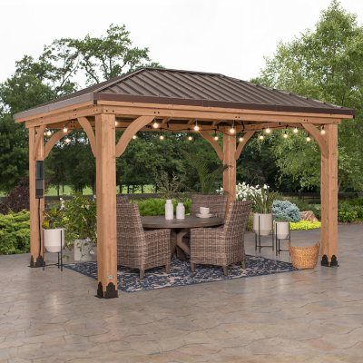 a wooden gazebo sitting on top of a patio next to a table and chairs