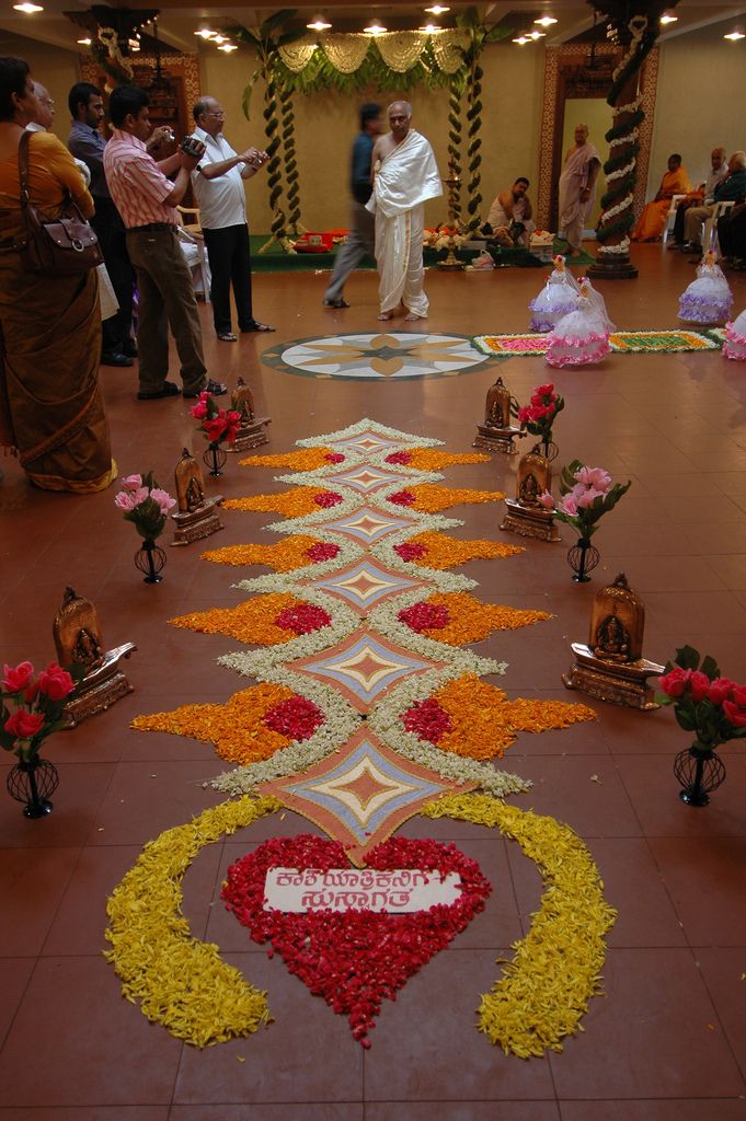 a group of people standing in a room with flowers on the floor and decorations around them