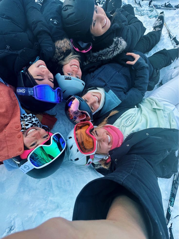 a group of people laying on top of snow covered ground with skis and goggles