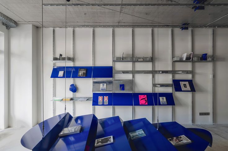 an empty room with blue tables and shelves on the wall in front of it,