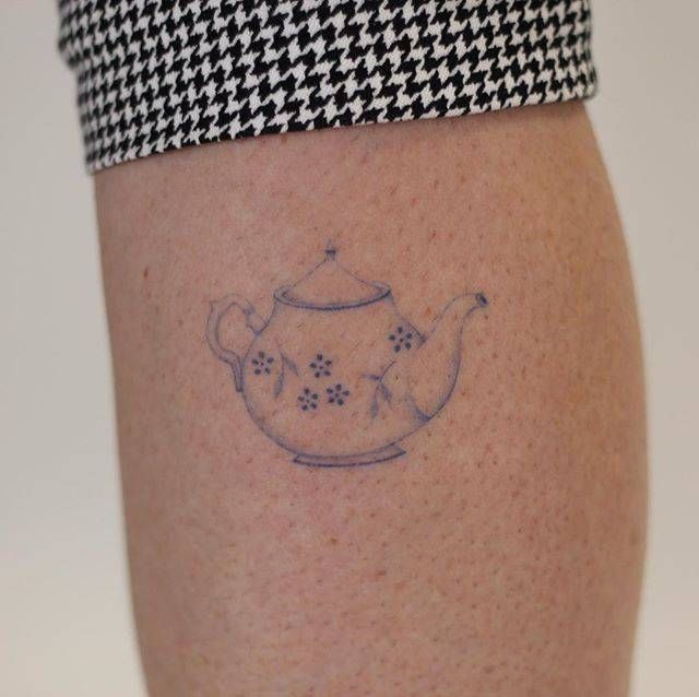 a tattoo on the leg of a woman with a teapot and flowers in it