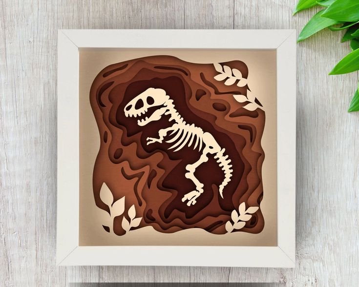 a paper cut out of a dinosaur in the shape of a rock with leaves on it