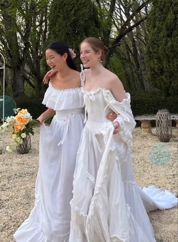 two women in white dresses standing next to each other