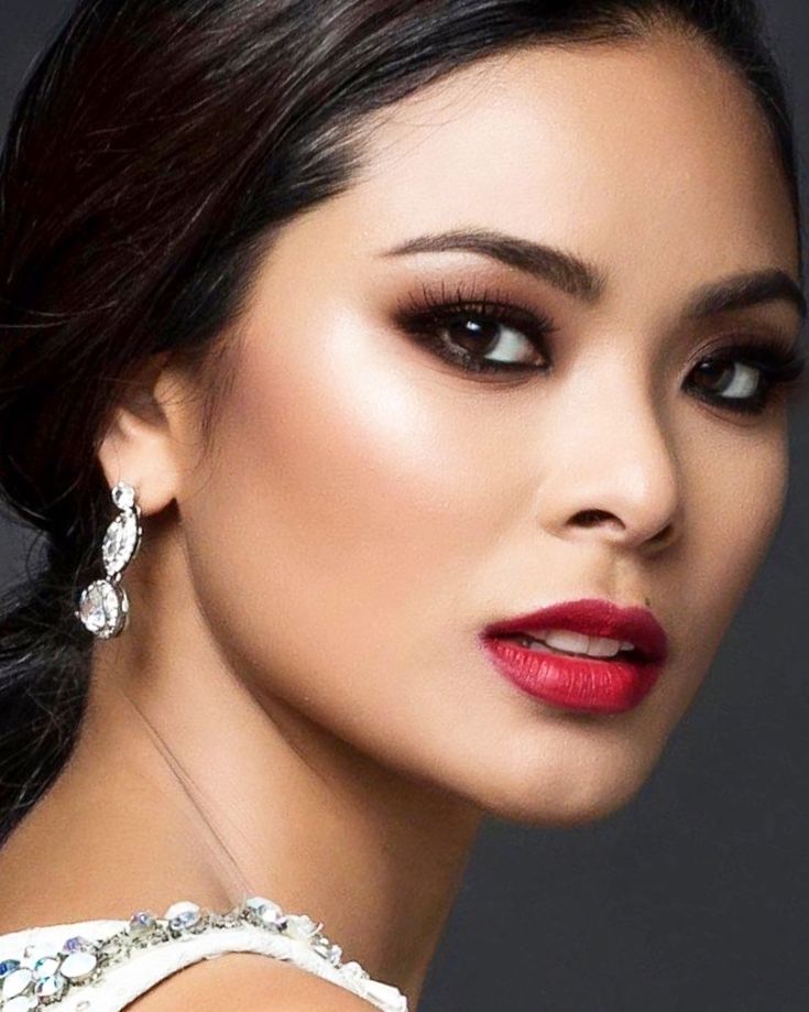 a woman in a white dress with red lipstick and earrings on her head, looking at the camera