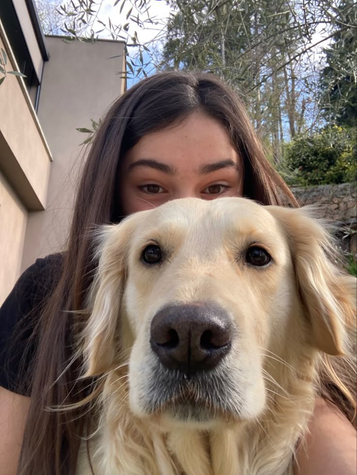 a woman is holding her dog in front of her face and looking at the camera