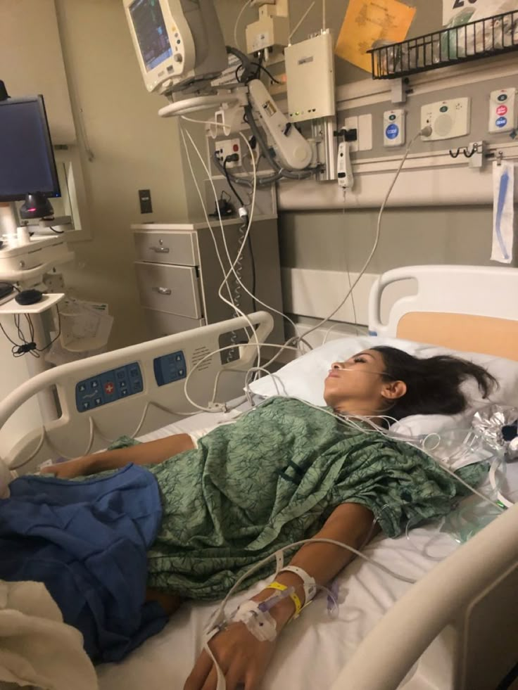 a woman laying in a hospital bed with an iv and monitors on the wall behind her