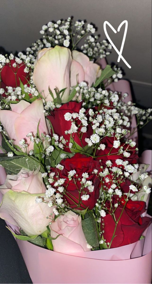 a bouquet of roses and baby's breath in a pink box