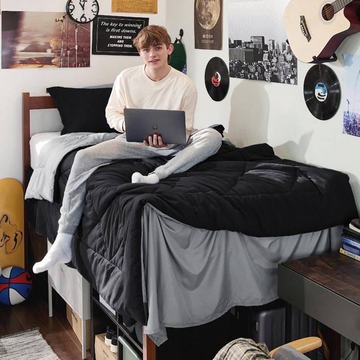 a man sitting on top of a bed using a laptop computer