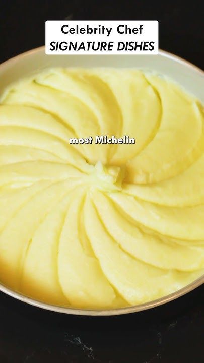 a white bowl filled with yellow food on top of a black table next to a spoon