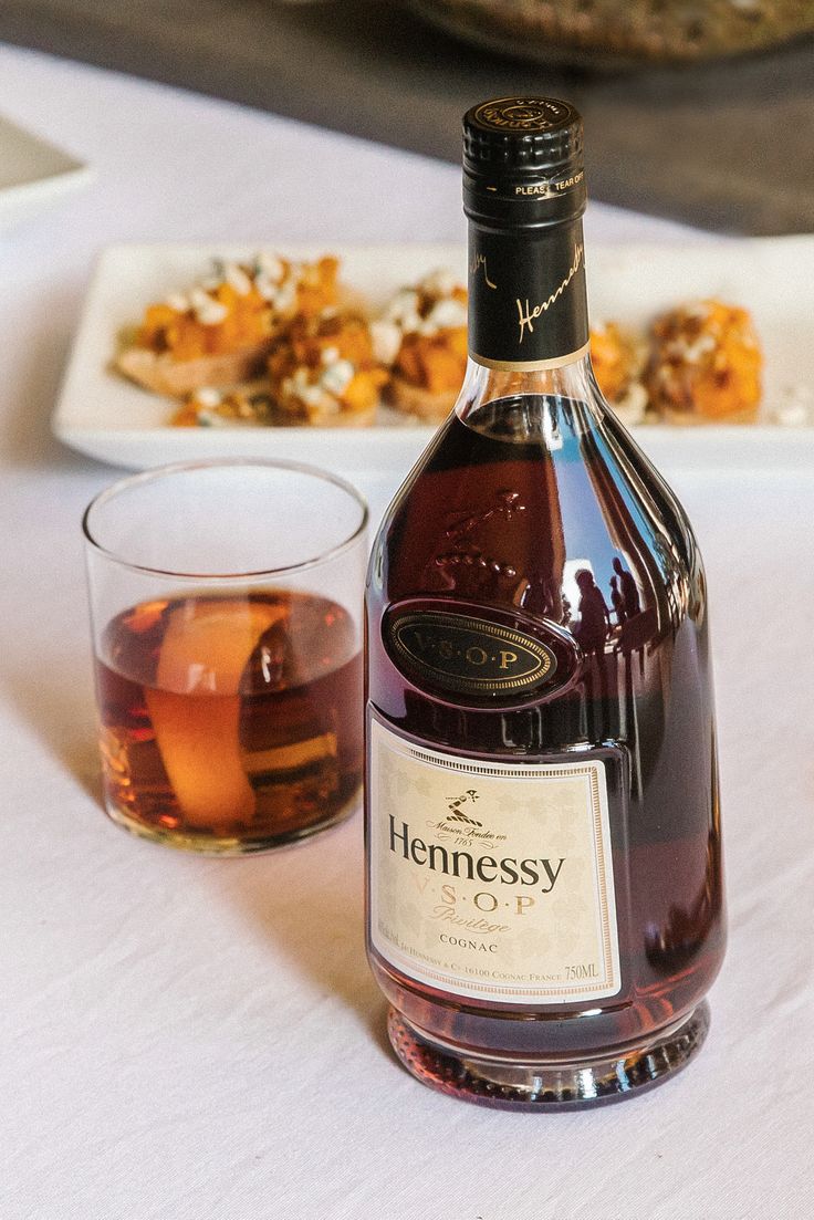 a bottle of hennessy on a table next to a glass and plate with food