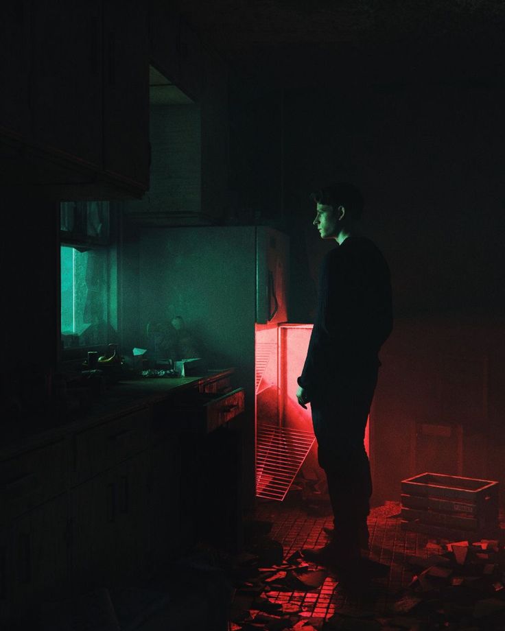 a man standing in a dark kitchen with red light coming from the ceiling and floor