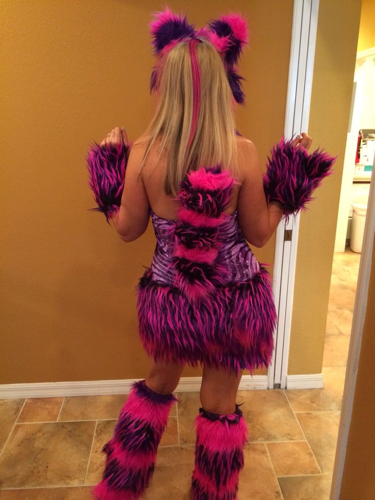 a woman dressed in pink and purple furry costume standing next to a door with her hands on her hips