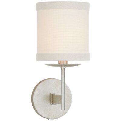 a wall light with a white shade on the side and a silver metal frame around it