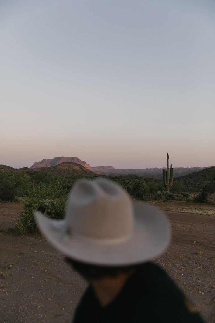 a man wearing a white hat standing in the desert