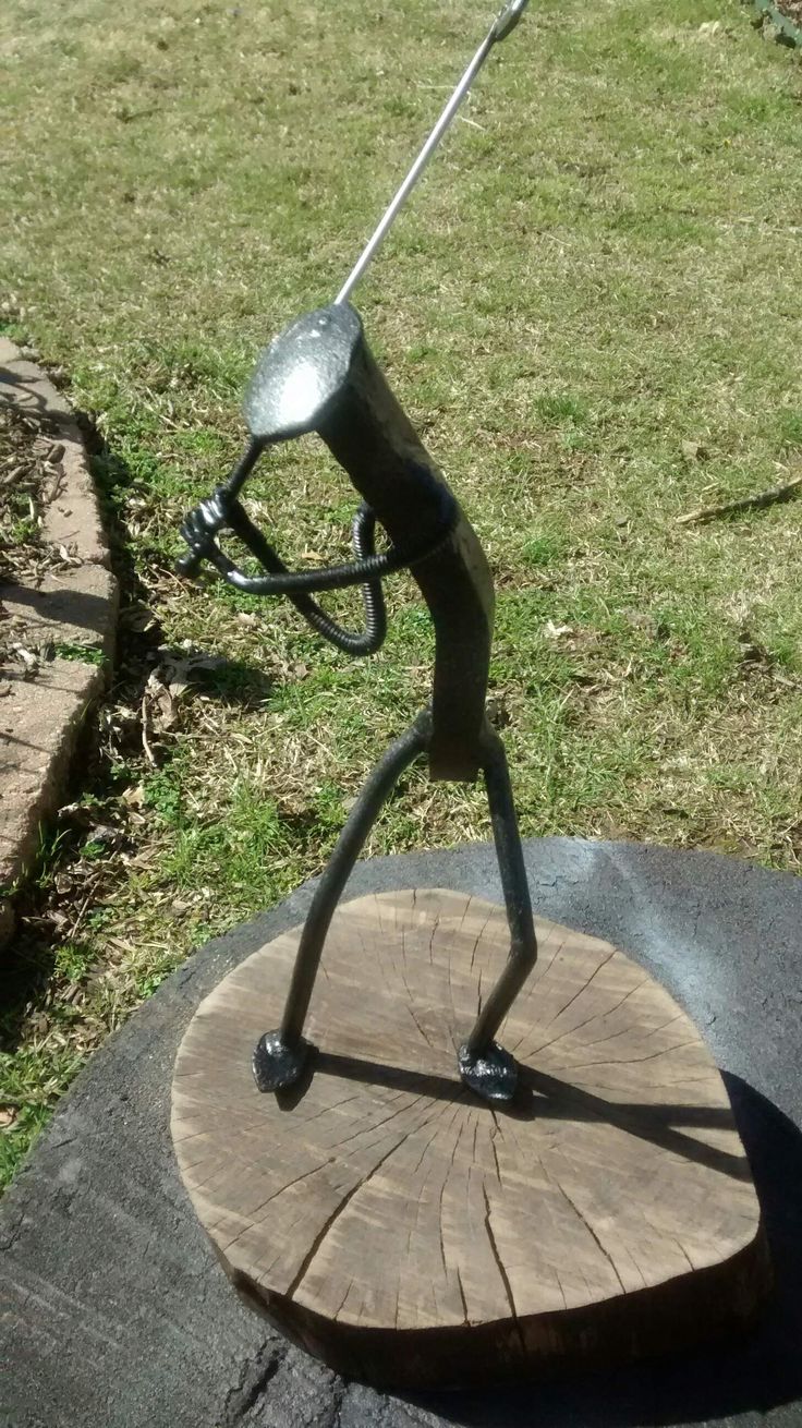 a metal figure on top of a piece of wood in the middle of a yard