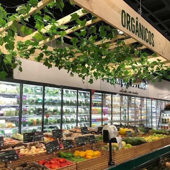 the produce section of a grocery store filled with fresh fruits and vegetables, hanging from the ceiling