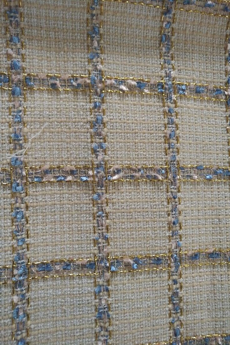 closeup of the fabric with blue and beige squares on it, as well as some gold thread