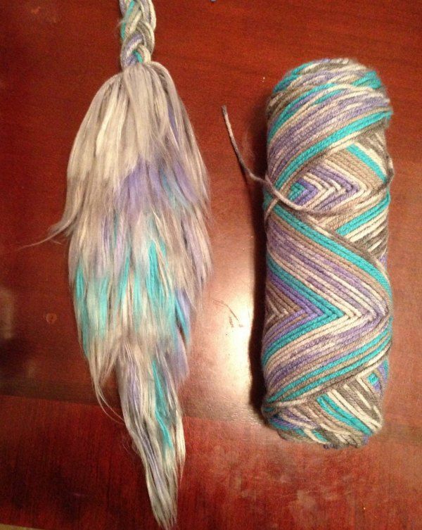 two skeins of yarn on a table next to a ball of yarn with feathers