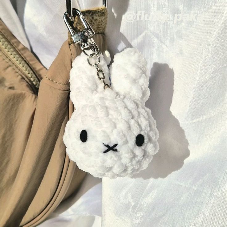 a white stuffed animal keychain hanging from a purse