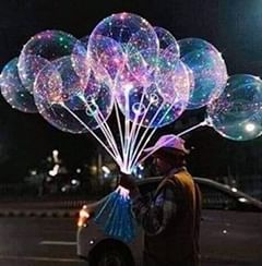 a man standing next to a car holding up large bubbles on top of his head