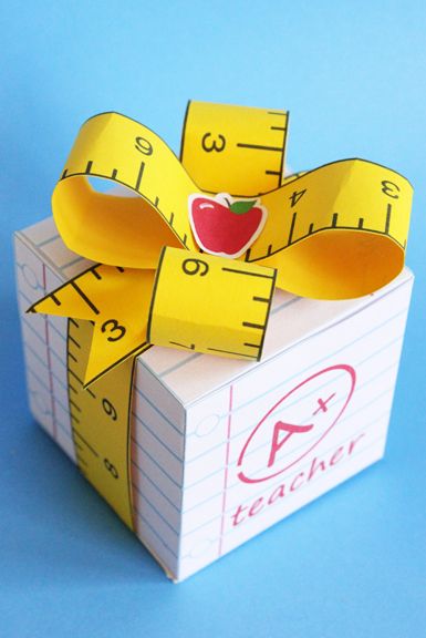 an apple and measuring tape on top of a cardboard gift box with the word teacher written on it